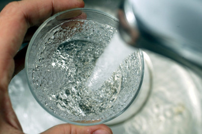 Wasser aus Hahn fließt in ein Trinkglas